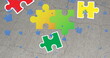 Person not visible, only colorful puzzle pieces scattered on gray surface