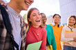 Laughing Caucasian female student with multiracial group of classmates posing hugging together for photo. Generation z friends smiling and having fun holding backpacks outdoor university campus