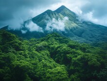 A Mountain Covered In Lush Green Trees And A Cloudy Sky