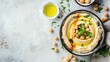 Bowl of hummus topped with chickpeas, olive oil, and parsley on textured surface