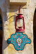 Close up view of the wall with a vintage metal lantern under which a blue floral pattern is painted in enamel, at Souq Waqif bazaar, at daytime, Doha, Qatar
