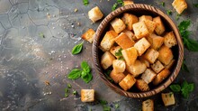 Bowl Of Golden-brown Croutons On Textured Surface With Fresh Basil Leaves