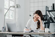 © Satori Studio - Focused woman meticulously sorts through paperwork, managing her tasks at an organized office desk.