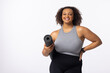 A biracial young female plus size model holding a yoga mat, standing confidently on white background