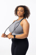 A biracial young female plus size model holding a jump rope on a white background