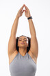 Biracial young female plus size model stretching arms up, eyes closed, on white background