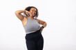 Biracial young female plus size model posing confidently on white background, hand on hip and behind