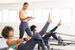 © Wavebreak Media - Diverse group of women practicing pilates on reformers in studio, copy space