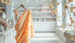 © ladyalex - Saree Indian dress in white luxury boutique background. Indian attire in fashion store. Festive outfit. Beautiful Bollywood clothing. Stylish orange party dress. Handloom saree salon. Banner