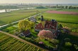 A historic Dutch manor house surrounded by tulip fields in full bloom, with colorful windmills dotting the landscape and picturesque canals nearby, Generative AI