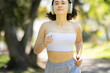 A woman is running in a park with her headphones on