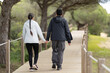 A man and woman are walking on a wooden bridge