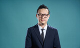 Fototapeta Miasto - Confident businessman with glasses on teal background