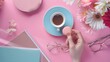 © Generative AI - Woman hand hold cup of coffee cake macaron clean notebook eyeglasses and flower on pink table from above Female working desk Cozy breakfast Flat lay style : Generative AI