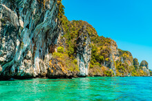 Large Rock Cliffs Covered With Green Trees Face Directly To The Vast Andaman Sea. The View Of Rock Cliffs And The Ocean Is An Icon Of Tropical Tourism On Phi-phi Island In Thailand