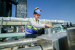 Skilled mechanical engineer conducts inspections on rooftop machinery with a backdrop of high-rise buildings and a bright blue sky.