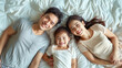 © aekkorn - Happy Asian family laying on bed smile.
