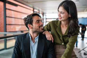 Two happy business woman and man using laptop working on computer at workplace. Cheerful young professional multiethnic colleagues team discussing online digital technology corporate project in office