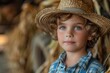 Smiling child with curly hair and striking blue eyes wears a straw hat against an agricultural backdrop