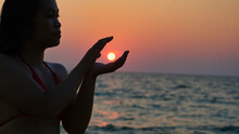 A Woman In A Silhouette Is Posing As If She Is Holding The Sun With Her Pair Of Hands.