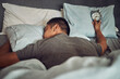 Man, sleeping and bed with alarm clock or tired insomnia for bad time management, depression or dreaming. Male person, pillow and lazy snooze in home or overworked burnout, mental health or Monday