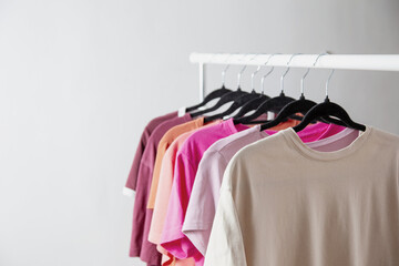 Sticker - row of t-shirts on a hanger against a background of a white wall hanger