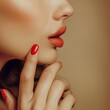 Close-up of woman's lips and red manicured nails, embodying sophisticated charm and style.