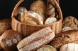 Wicker basket with different types of fresh bread against black background