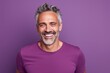 Portrait of a grinning man in his 50s donning a trendy cropped top over solid color backdrop