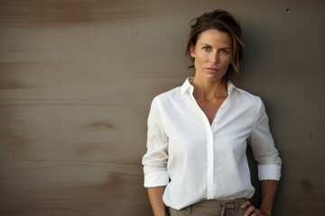 Wall Mural - Portrait of a glad woman in her 40s wearing a classic white shirt isolated on bare concrete or plaster wall