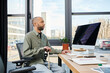 © Bliss - disabled african american man with myasthenia gravis sits at a desk engrossed in his work, facing a computer screen in an office setting typical of corporate culture.