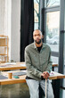 © Bliss - disabled man with myasthenia gravis in business attire sitting atop a wooden table, immersed in thought, surrounded by an office environment.