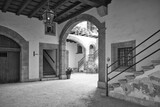 Fototapeta  - A beautiful courtyard - a backyard, shot through a gate, in black and white