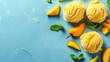 Mango ice cream scoops with fresh mango pieces and mint leaves on blue background