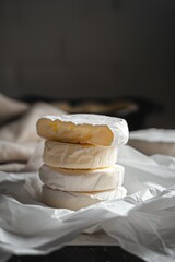 Sticker - A close-up view of stacked wheels of creamy cheese with one wheel cut open