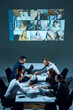 © master1305 - Business professionals seated around table in office conference room, communicating with remote team members via video call. Working with strategy and analytics. Business, entrepreneurship, team