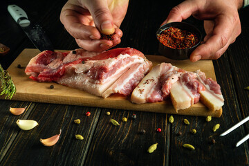 Wall Mural - Pork cherve sliced on a kitchen board. The cook adds aromatic spices to the lard by hand.