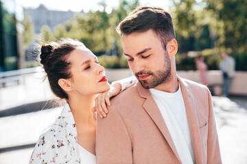 Wall Mural - Beautiful fashion woman and her handsome elegant boyfriend in beige suit. Sexy brunette model in summer clothes. Fashionable smiling couple posing in street Europe. Brutal man and female outdoors