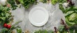 Top view of a light grey marble kitchen countertop adorned with fresh raw greens, unprocessed vegetables, and grains, with a white plate in the center. Copy space available.