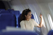 © Kainnika - Lonely Asian female tourist traveling alone on a plane looking out the window, She is thinking of someone.