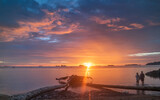 Fototapeta Zachód słońca - Beautiful calm view of sunset at beach with a couple
