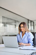 © insta_photos - Busy middle aged business woman using laptop working in office. Vertical shot of mature businesswoman entrepreneur at work, smiling professional female company executive manager looking at computer.