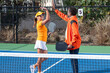 © Mat Hayward - Two pickleball players give each other a high five after winning a match on an outdoor court. The man and woman are celebrating together after a successful game.