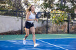 © Mat Hayward - Asian woman playing pickleball on a court with her paddle outside. The female player is strong and plays hard.