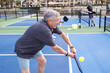 © Mat Hayward - Mature man playing pickeball. He is hitting the ball with his paddle.