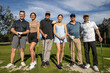 © Mat Hayward - Group of golfers standing together outside on a golf course. The six friends are holding clubs on a sunny day, happy to play the game.