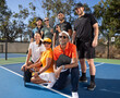 © Mat Hayward - Group of seven friends together on pickleball court. The diverse players are laughing and smiling together outside and having fun. Multi-ethnic people and diversity in age and gender.