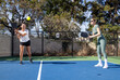© Mat Hayward - Two female pickleball players work together as a team during a game on an outdoor court.