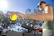 © Mat Hayward - Female pickleball player holding the ball and her paddle about to serve in an outdoor game. She is wearing sunglasses and her arm and forearm in the center frame.