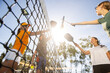 © Mat Hayward - Four pickleball players tapping racquets over the net after a fun game in the sun outside.